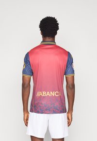 Sarkans un zils futbols krekls ar īsām piedurknēm, apkakli, dzelteniem akcentiem un logotipu "ABANCA" aizmugurē. Rūpīgi tekstūrēts gradienta dizains.