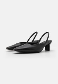 Svarte slingback-hæler med spiss tå, glatt lærmateriale, kort blokkhæl og gjennomsiktige sidedele for et moderne design.