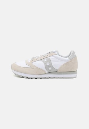 Sneaker bianca e grigia chiara con un mix di texture lisce e scamosciate, punta arrotondata e tre accenti circolari sul lato.