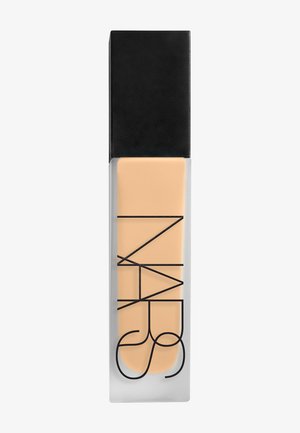 Bouteille rectangulaire en verre dépoli avec un bouchon noir, contenant du fond de teint liquide beige ; logo NARS imprimé en grandes lettres noires sur le devant.