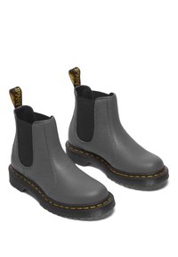 Botas Chelsea de cuero gris con paneles elásticos laterales, un acabado texturizado, costuras amarillas y una suela de goma negra con un ligero tacón.