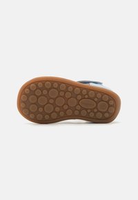 Rubber shoe sole with circular textured patterns, tan color, featuring a smooth edge, and embossed brand name "bisgaard."