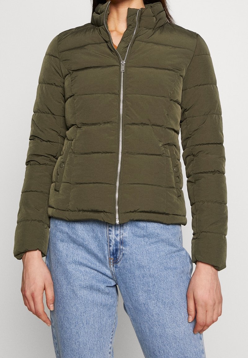 Olivengrøn dynejakke med høj krave, lynlåslukning og vandret quiltet mønster. Har to sidelommer og en kort pasform.