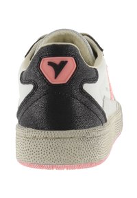 Sneaker con tomaia in pelle bianca, tallone nero testurizzato, accento rosa e suola beige a pois. Presenta un badge con logo sul tallone.