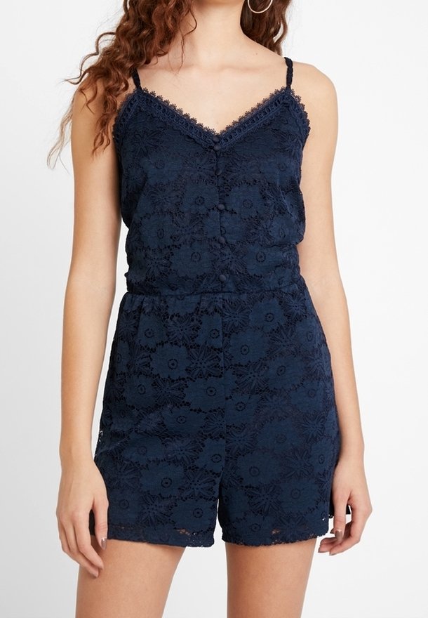 Combinaison-short en dentelle bleu marine avec bretelles spaghetti réglables, motif floral, encolure en V et détail de boutons à l'avant. Texture douce.