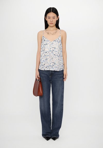 Light blue floral print camisole with thin straps, paired with wide-leg dark denim jeans. Model holds a small brown handbag.