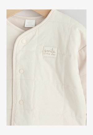 Párnázott baba dzseki puha bézs pamutból, steppelt mintával, patentgombokkal, "mosolyogj kicsim" felirattal ellátott folttal.