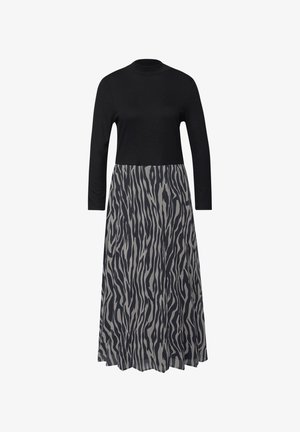 Schwarzes, langärmeliges Oberteil mit hohem Kragen und fließendem grauem Rock mit schwarzem, abstraktem Zebra-ähnlichem Muster.