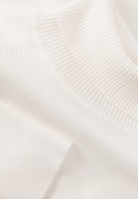 Weißer Strickpullover mit geripptem Ausschnitt und weicher Textur, der durch den glatten Stoff ein sauberes, minimalistisches Erscheinungsbild verleiht.