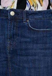 Jeanskjol med mörkblå tvätt, med knappstängning fram, fem fickor och rak passform med synliga sömnadsdetaljer.