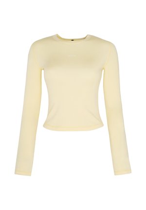 Chemise ajustée à manches longues, jaune clair, avec col rond et petit texte blanc centré sur la poitrine.