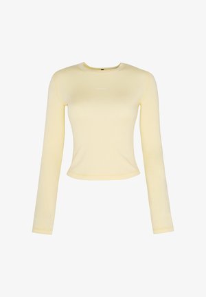Chemise ajustée à manches longues, jaune clair, avec col rond et petit texte blanc centré sur la poitrine.