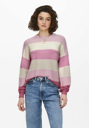 Pull rayé rose et crème avec des manches longues, texture côtelée, coupe oversized, associé à un jean bleu taille haute.