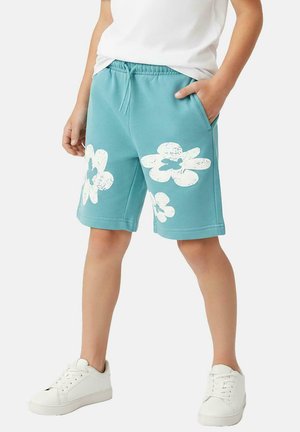 Turquoise shorts gemaakt van katoenmix, met witte bloemenprints. Ontworpen met een elastische tailleband en zijzakken. Gecombineerd met witte sneakers.