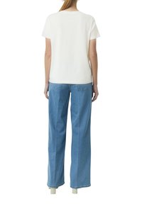 Witte katoenen t-shirt met korte mouwen en ronde hals, gecombineerd met lichtblauwe wijde denim jeans met twee achterzakken.