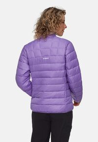 Lila puffjacka med kviltat mönster som visar en slät textur och logodetaljer på baksidan. Lätt och figurnära silhuett.