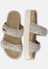 Witte sandalen met zwart gespikkeld ontwerp, twee brede banden over de bovenkant, beige suede voetbed en een gestructureerde witte rubberen zool.