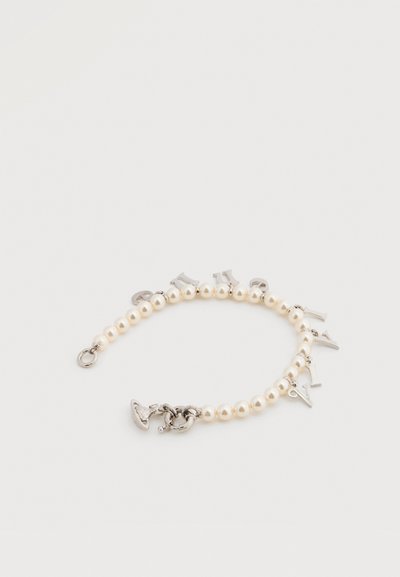 Βραχιόλι με πέρλες που διαθέτει μεταλλικά γράμματα ως διακοσμητικά στοιχεία. Χρώμα: λευκές πέρλες με ασημένιες λεπτομέρειες. Ο σχεδιασμός περιλαμβάνει κούμπωμα τύπου αστακού και ομαλή υφή.