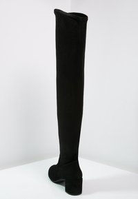 Bota negra por encima de la rodilla hecha de suave ante, con punta redondeada y un tacón grueso. Textura suave con un diseño sin costuras.