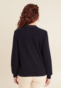 Maglione lavorato a maglia blu navy con un motivo testurizzato, scollo a girocollo e polsini a coste. Il retro presenta un design semplice e pulito.