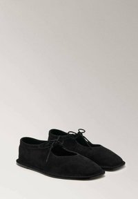 Chaussures en daim noir avec un bout allongé, des côtés ouverts et des lacets en haut. Finition texturée et semelle plate. Design simple et minimaliste.