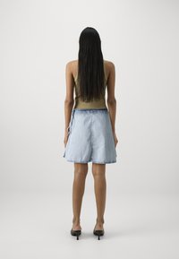 Lys olivengrønn tanktop kombinert med en kne-lengde lys blå denimskjørt. Skjørtet har en blyantsilhuett og råkant. Enkle svarte hæler fullfører antrekket.