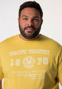 Žluté bavlněné tričko s bílým potiskem: "TROUT TROPHY 1978" a "OUTDOOR & WILDLIFE", kulatý výstřih, krátké rukávy, volný střih.