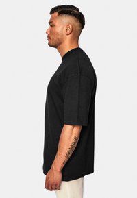 Sort kortærmet T-shirt med klassisk rund hals, lavet af blødt bomuldsmateriale med en afslappet pasform og minimale syninger.