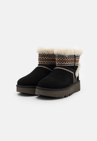 Botas negras de ante hasta el tobillo con forro de piel sintética crema, banda de tela estampada y suela de goma texturizada con surcos profundos para mayor tracción.