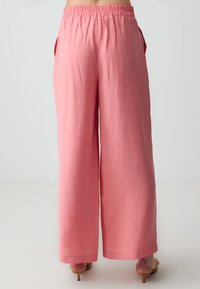 Roze wijde broek van een zachte, lichte stof, met een elastische tailleband en zijzakken voor extra gemak.