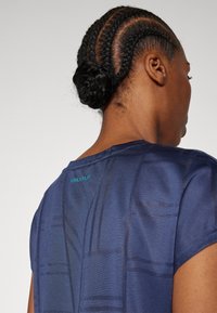 Marinblå atletisk T-shirt med korta ärmar, med ett texturerat mönster och turkos "ONLY PLAY"-logotyp vid bakre nacklinjen.