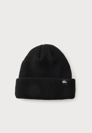 Bonnet en maille noire avec revers plié et petit patch logo rectangulaire sur le devant, sur un fond clair uni.
