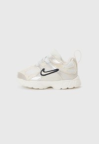 Bottines de sport pour enfant avec une tige en maille blanche, des accents métalliques argentés, un logo noir et une semelle texturée. Comprend une languette rembourrée et une bride de traction.
