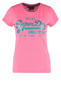 Camiseta de algodón rosa con mangas cortas que presenta un diseño gráfico brillante en turquesa que dice "REAL SuperDry" en el pecho.
