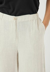 Lysfarget, linblandede bukser med vertikale blå striper, som har knappelukking, sidelommer og en avslappet passform.