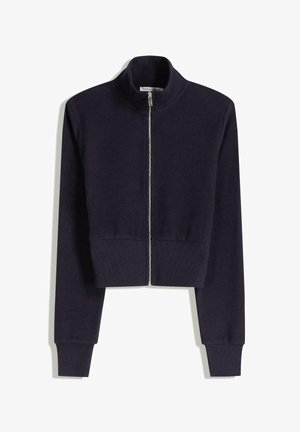 Tummansininen lyhyt vetoketjullinen takki, jossa on pitkät hihat, ribbattuja hihansuita ja korkea kaulus.