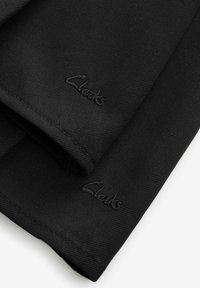 Schwarzer Stoff mit einer strukturierten Oberfläche, der ein gesticktes "Clarks"-Logo nahe dem Rand aufweist. Das Material ist robust und glatt.