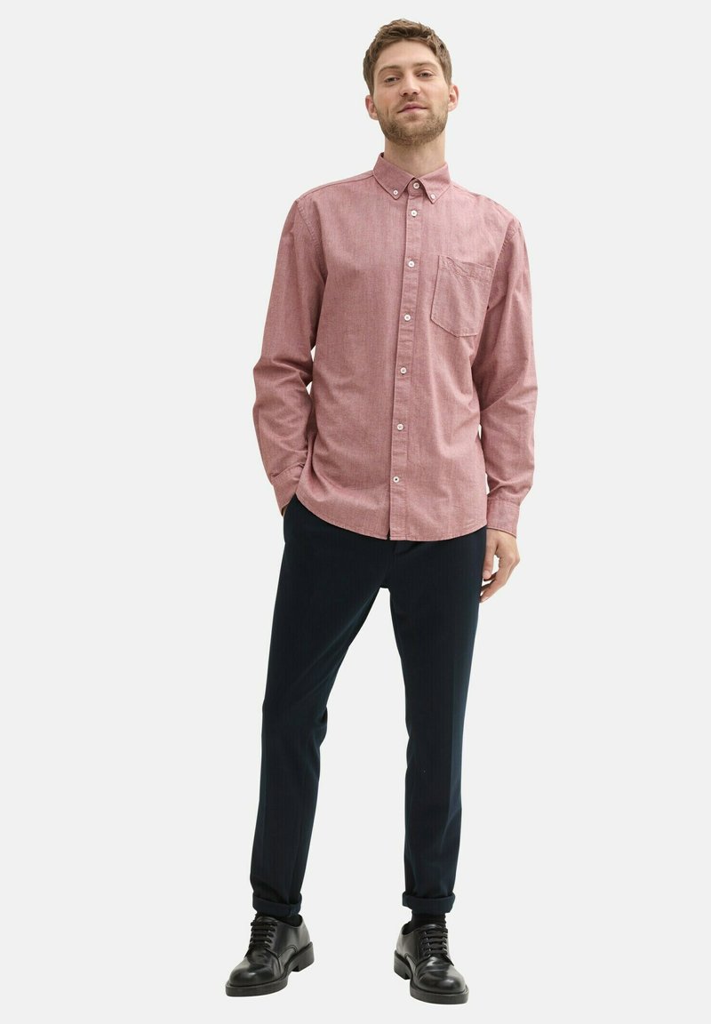 Camicia button-up a quadri rossi con tasca sul petto, abbinata a pantaloni scuri su misura e scarpe nere stringate. Texture in cotone liscio.