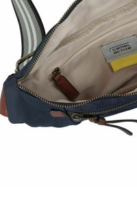 Navyblauwe canvas tas met een beige voering, voorzien van een ritsvak en leren accenten. Verstelbare gestreepte schouderband zichtbaar.