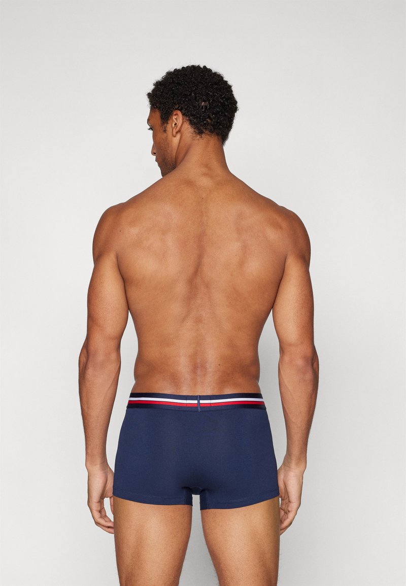 Boxer-briefs bleu marine au design ajusté, avec une ceinture rayée multicolore. Le matériau semble lisse et extensible.