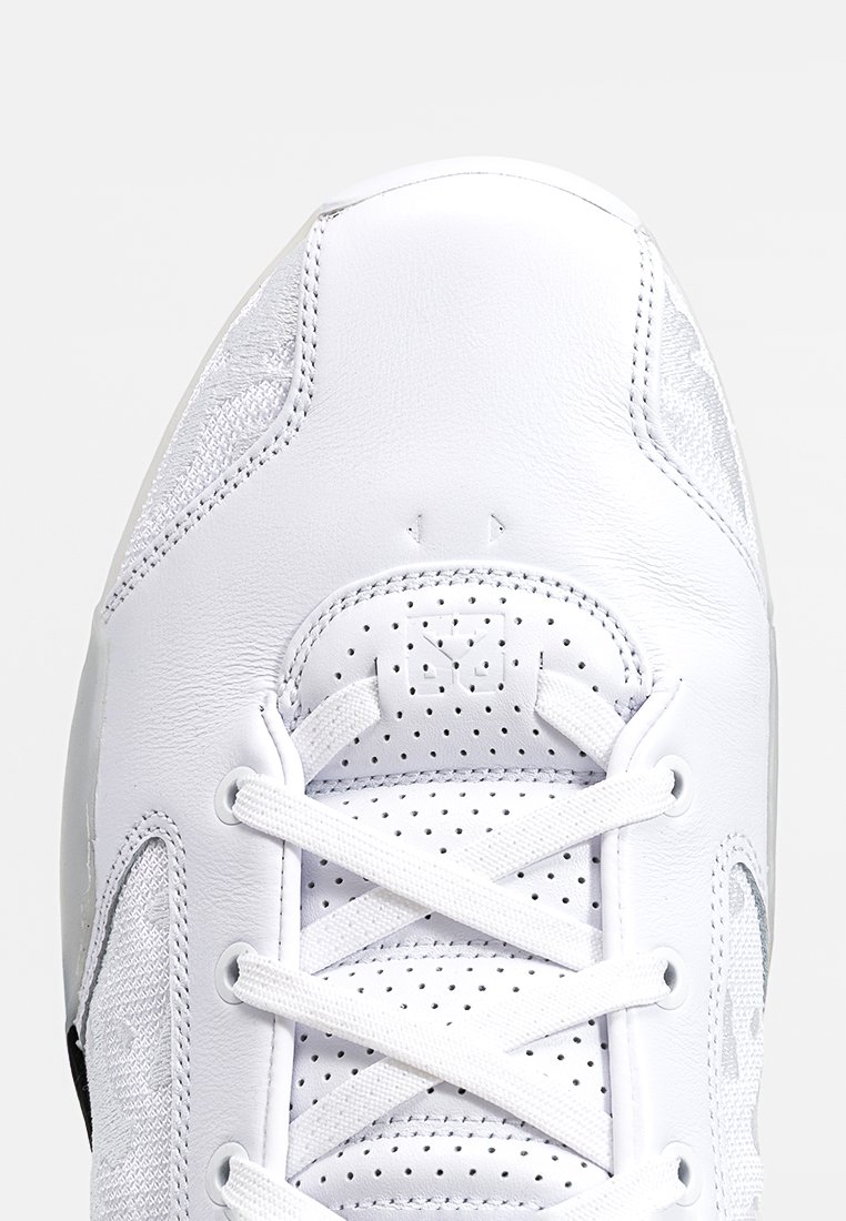 Zapatilla deportiva blanca con un upper de cuero suave, lengüeta perforada, cordones planos y un acento negro en el costado. Detalle de costura reforzada.