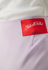 Lavendel stof met een gladde textuur, voorzien van een prominente rode label met de tekst "Dat is alles, Folks!" en "MAX&Co." in witte letters.