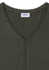 T-shirt vert olive foncé col en V avec surpiqûres décoratives autour de l'encolure et une étiquette blanche portant la mention « CECIL » au col.