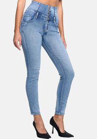 Jeans skinny de tiro alto en denim azul claro con una cinturilla de cinco botones, bolsillos frontales y una silueta ajustada y elegante con ligeras arrugas.