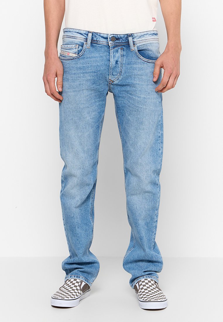 Jeans in denim blu chiaro con taglio dritto, dotati di cinque tasche e lavaggio sbiadito. Abbinati a scarpe slip-on a quadri.