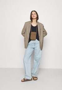 Blazer beige oversize, top nero, jeans larghi azzurri, borsa a tracolla marrone e sandali marroni. Un outfit semplice e funzionale.