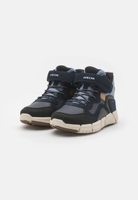 Ciemnoniebieskie sneakersy z czarnymi zamszowymi akcentami, z wyściółką w kołnierzu i teksturowaną gumową podeszwą. Charakteryzują się wiązaniem na sznurówki oraz paskiem na rzep.