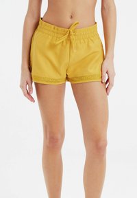 Gele shorts met elastische taille en een trekkoord, versierd met kant langs de onderrand. Zachte stof met een gladde textuur, geschikt voor casual kleding.