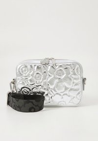 Metalen zilveren tasje met geprofileerd bloemmotief, ritssluiting en afneembare zwarte band met patroon voor veelzijdige draagmogelijkheden.