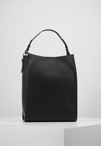 Czarna skórzana torebka z teksturowanym wykończeniem, z jedną regulowaną rączką na ramię i geometrycznym akcentem z przodu.